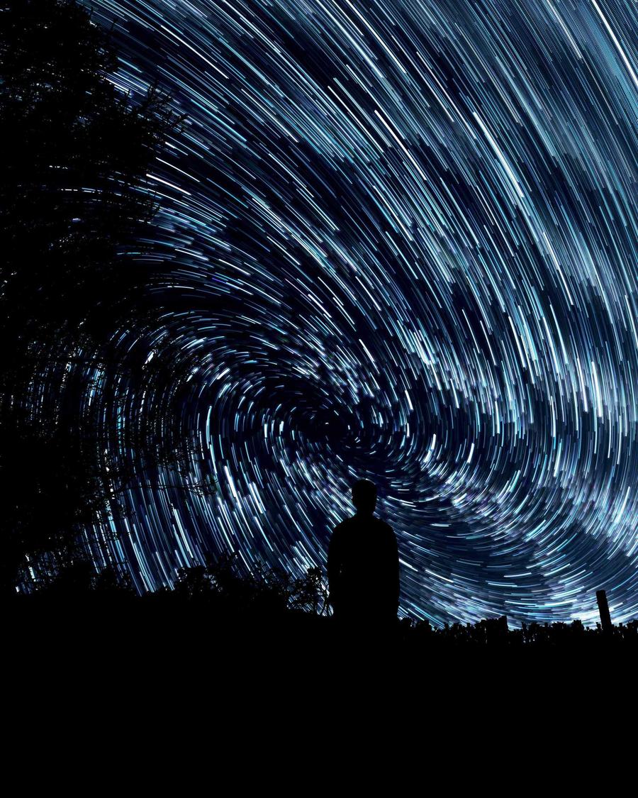 Filés d'étoiles en spirale au-dessus d'une silhouette immobile